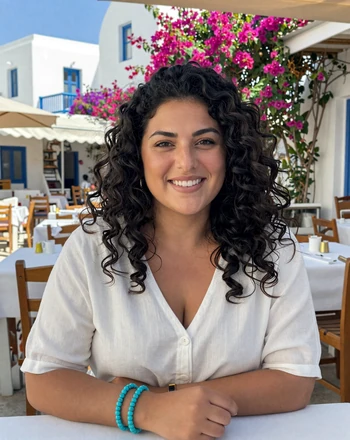 Eleni, 30, Greek woman from Athens with radiant smile at an outdoor taverna
